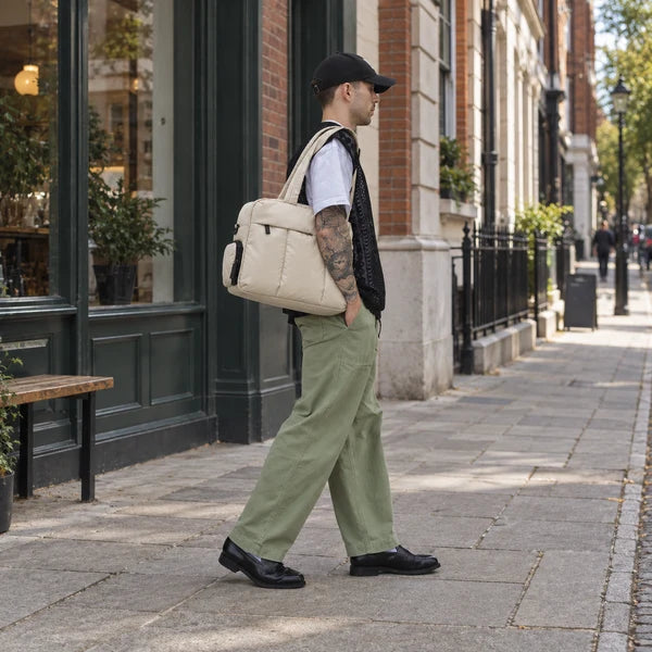Illustrative photo of a man in a brown sweater carrying the Cream All-Day Tote on a city street